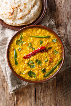 Indian popular food Dal Tadka Curry served with roti flatbread close-up. Vertical top view