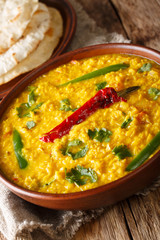 Lentil soup Dal Tadka with naan bread in a ceramic bowl on a wooden background. Vertical