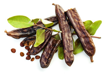 Carob beans. Healthy organic sweet carob pods with seeds and leaves on white background