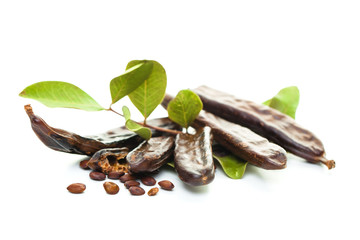 Carob. Healthy organic sweet carob pods with seeds and leaves on white background
