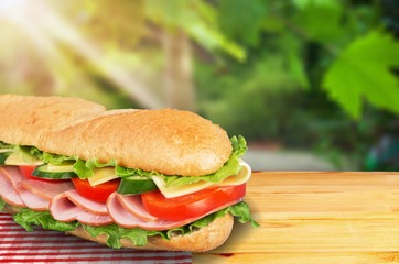 Long baguette sandwich with lettuce, vegetables, ham,