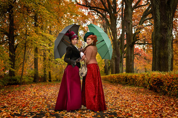 Obraz na płótnie Canvas Two beautiful women with umbrellas in the park