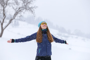 Fototapeta na wymiar Young slim woman enjoying snowy weather in winter