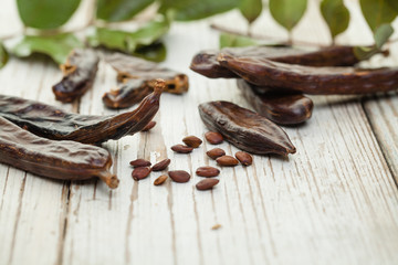 Carob on white wooden background.