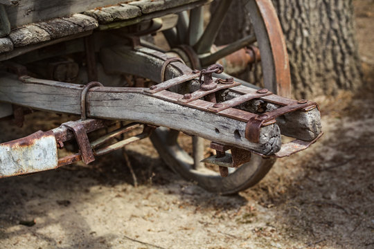 Close up of old rusty wooden wagon connecting mechanism, wheel visible in background