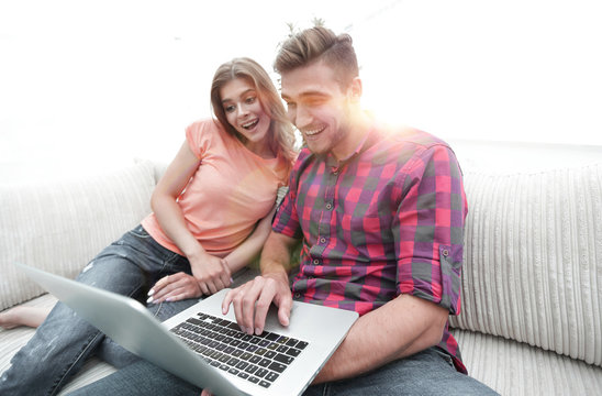 Happy modern couple surfing the net and working on laptop at home