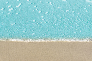 Soft wave of blue ocean on sandy beach. Background / Sand and wave at the beach background. Drop space on bottom for text and other.