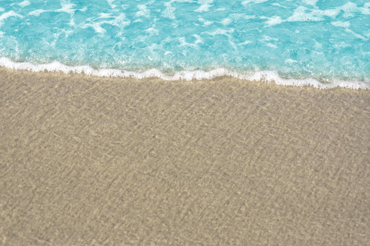 Soft wave of blue ocean on sandy beach. Background / Sand and wave at the beach background. Drop space on bottom for text and other. © NOKFreelance