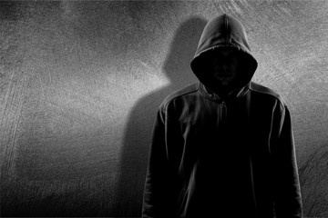 Dark unrecognisable man in hoodie on background