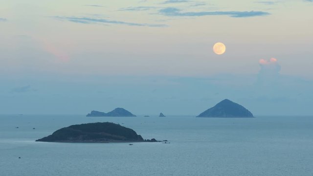 The full moon rising over the sea at sunset