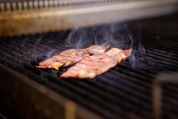 Delicious smoked bacon on grill in kitchen restaurant. Food preparation
