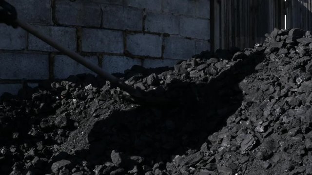 Man with shovel and heap coal. mini coal boiler-house. preparation for winter season. slow motion