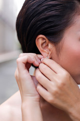 Fototapeta premium Beautiful, happy bride dresses earrings Wedding accessories, jewelry. Closeup portrait of bride. Selective focus.