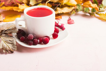 Autumn concept with red cranberry beverage with dry leaves. Cozy home. Copy space