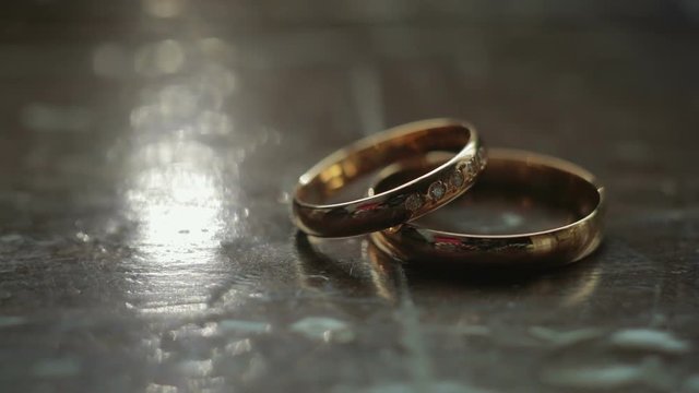Two wedding rings lie on a wooden surface. Close up