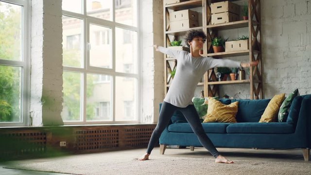 Athletic girl is doing sequence of strength and stretching yoga exercises at home during individual practice. Self-development, active lifestyle and people concept.