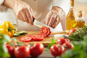 Chef slicing fresh tomatoes for a salad