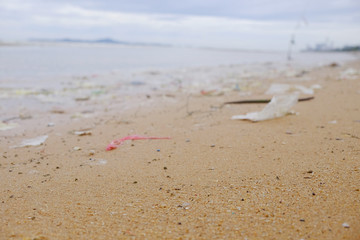 Beach pollution, trash on the beach, waste in the ocean with selective focus