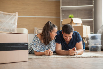 Couple moving in house sitting on the floor.Cheerful young couple