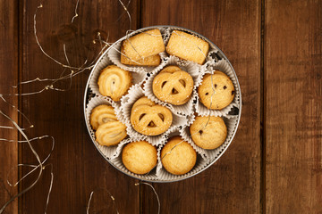 An overhead photo of Danish butter cookies in the traditional tin box, on a dark rustic background with Christmas lights and copy space