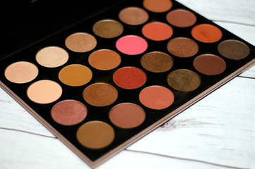 natural cosmetics, a palette of multi-colored eye shadows on a light wooden background