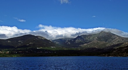 Fototapeta na wymiar Panorámica de lago, bosques, montañas nevadas, nubes y cielo azul.