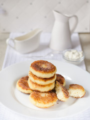 Cheese pancakes, curd cheese pancakes in cast iron frying pan on white background
