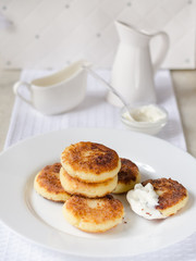 Cheese pancakes, curd cheese pancakes in cast iron frying pan on white background