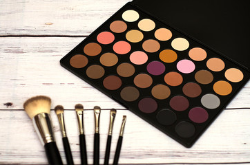 natural cosmetics, a palette of multi-colored eye shadows on a light wooden background