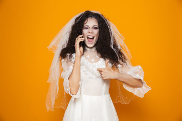 Happy dead bride talking on smartphone and showing thumb up isolated
