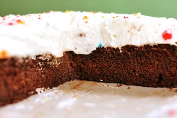 Chocolate birthday cake homemade, on a plate, decorated with colored candies on whipped cream