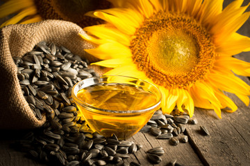 Closeup photo of sunflower oil with seeds on wooden background. Bio and organic product concept.