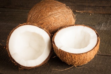 Ripe half cut coconut on a wooden background.. Coconut cream and oil.