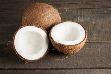 Ripe half cut coconut on a wooden background.. Coconut cream and oil.