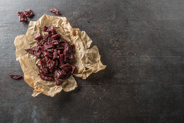 A pile of dried beef jerky pieces on paper and cutting board