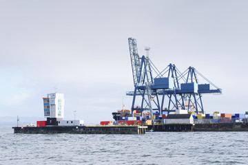 Fototapeta na wymiar Container terminal crane gantry for loading and offloading cargo freight shipping at quay yard harbour dock on sea coast Greenock Scotland UK