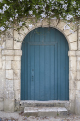 Fototapeta na wymiar Rustic blue wooden door with white flowers above