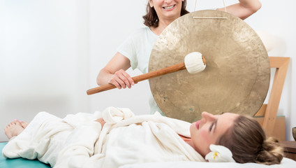 Smiling woman relaxing in spa while masseuse making sound