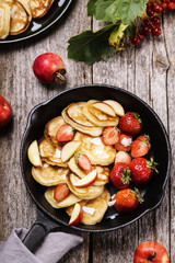 Cheese Buttermilk Pancakes or fritters with strawberry, sliced apples and coconut crunches on pan on vintage wooden table. Autumn breakfast
