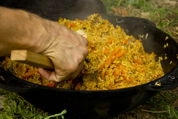Picnic in nature. Cooking pilaf in nature. Pilau cooked in the open air in a cauldron on an open fire. 