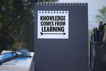 Educational and motivational  quote - &lsquo;Knowledge comes from learning&rsquo; written on a white paper. Blurred styled background.