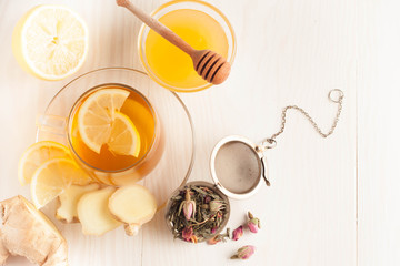 Closeup of cup of tea with tea leaves, mint on vintage wooden background. Black herbal tea with lemon, ginger and honey. hot winter drink