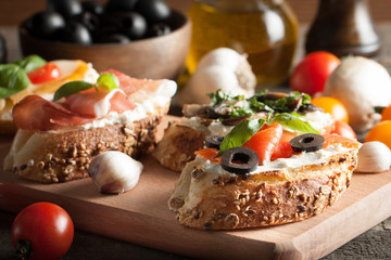 Italian tomato and cheese bruschetta. Tapas, antipasti with chopped vegetables, herbs and oil on grilled ciabatta and baguette bread.