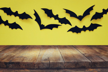 Halloween holiday concept. Empty rustic table in front of black bats background. Ready for product display montage.
