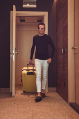 Smiling man with luggage getting in hotel room.