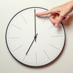 Woman hand stop time on a round clock, female finger takes the minute arrow of the clock back, time...
