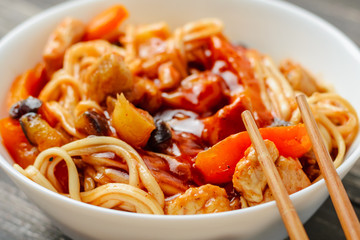 WOK udon noodle with chicken and vegetables in a white plate, close up