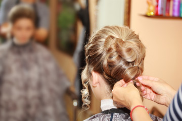 A young girl on the wedding day makes a beautiful hairstyle at the hairdresser.