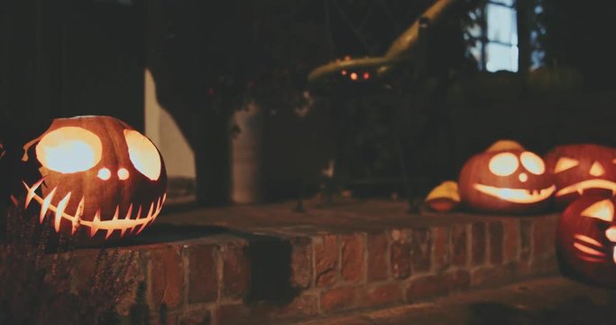 Halloween Carved Pumpkin on Front Porch. 4K. Jack-o'-Lantern decoration illuminating with burning candle inside. Autumn All Saints Day.