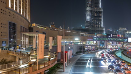 Car traffic on road near mall at night in downtown timelapse.